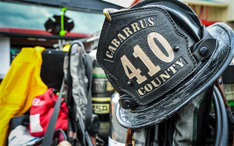 A firefighter helmet with Cabarrus County Squad 410 hangs near a group of firefighting equipment